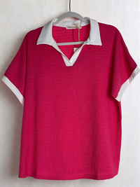 Red polo shirt with white collar and trim on a hanger against a white background