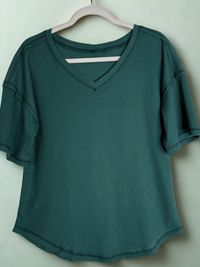 Green shirt on a hanger against a white background