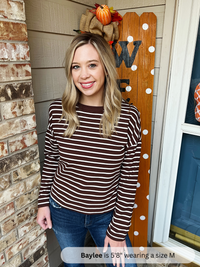 Woman wearing a striped shirt standing in front of a decorated door with pumpkins.