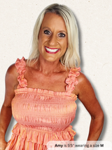 Woman wearing a peach dress with ruffled straps on a plain background