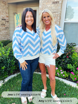 Two women wearing blue and white chevron patterned sweaters standing outdoors.