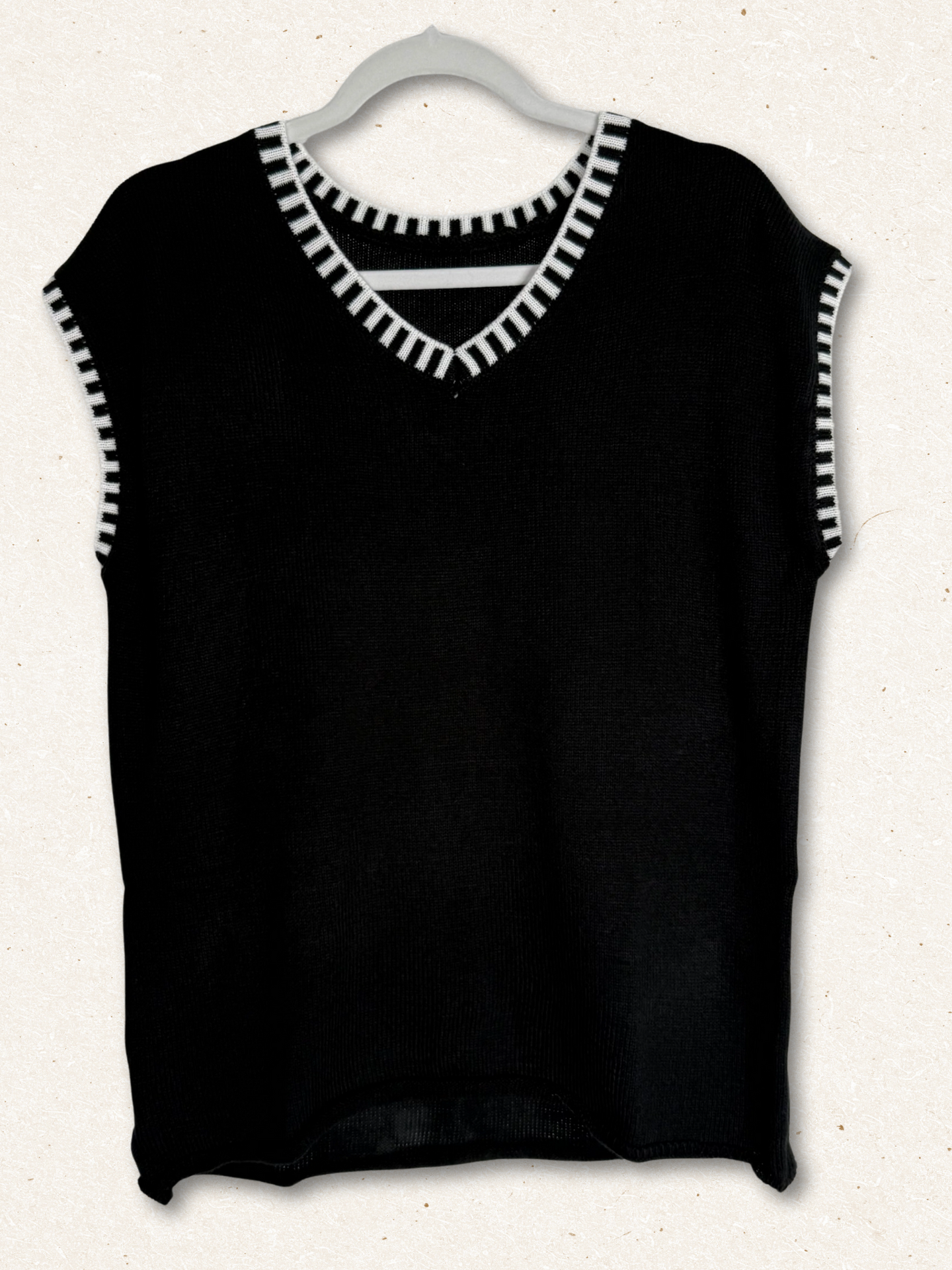 /Black/ Black sleeveless top with white trim on a hanger against a white background