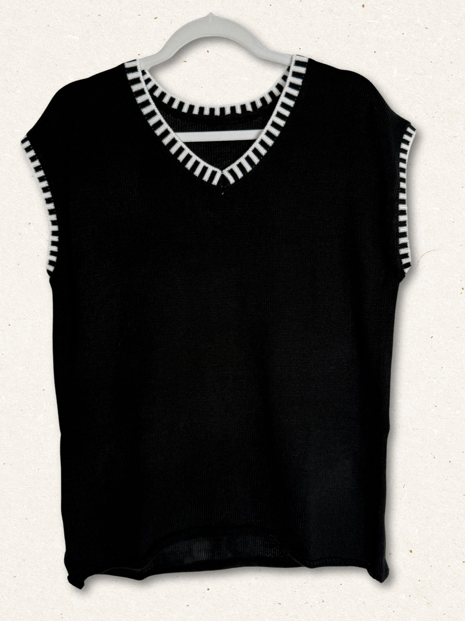 /Black/ Black sleeveless top with white trim on a hanger against a white background