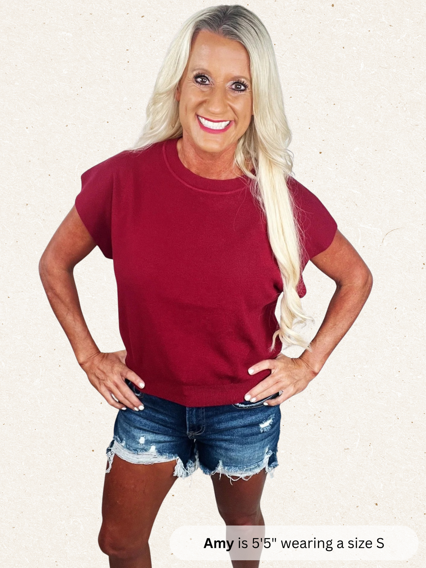 Woman wearing a maroon t-shirt and denim shorts on a white background