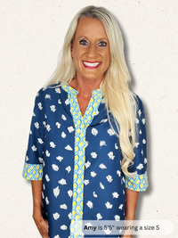 Woman wearing a blue patterned shirt with text indicating height and size.