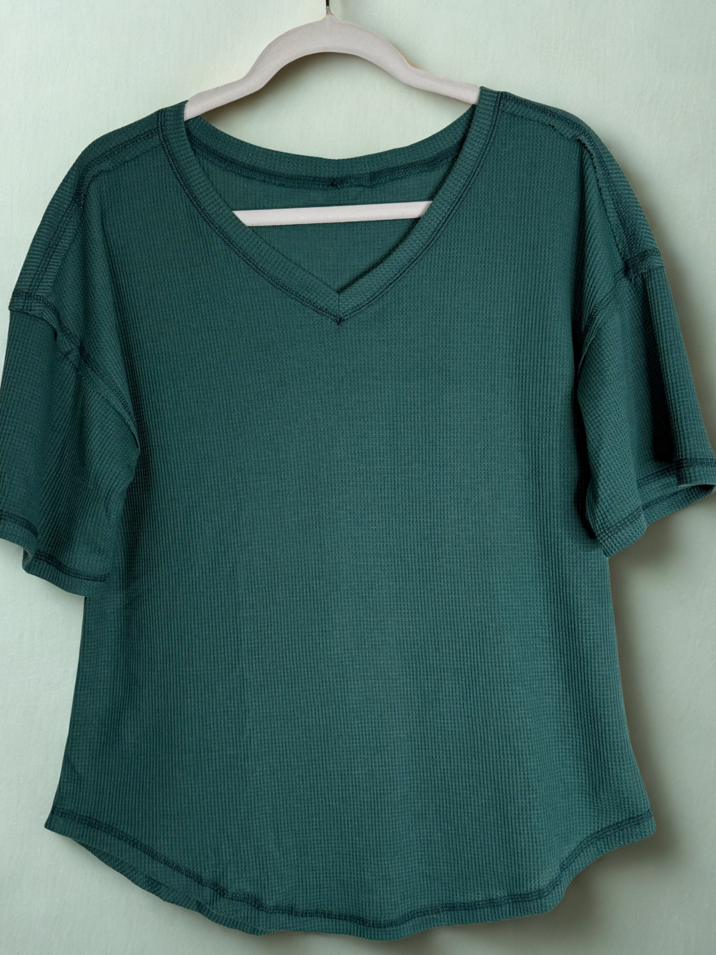 Green shirt on a hanger against a white background