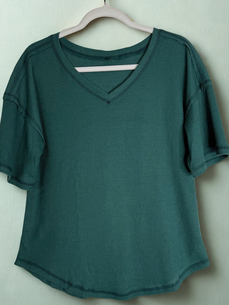 Green shirt on a hanger against a white background