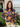 Woman wearing a navy blue floral blouse with orange flowers standing outside a house.