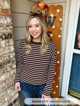 Woman wearing a striped shirt standing in front of a decorated door with pumpkins.