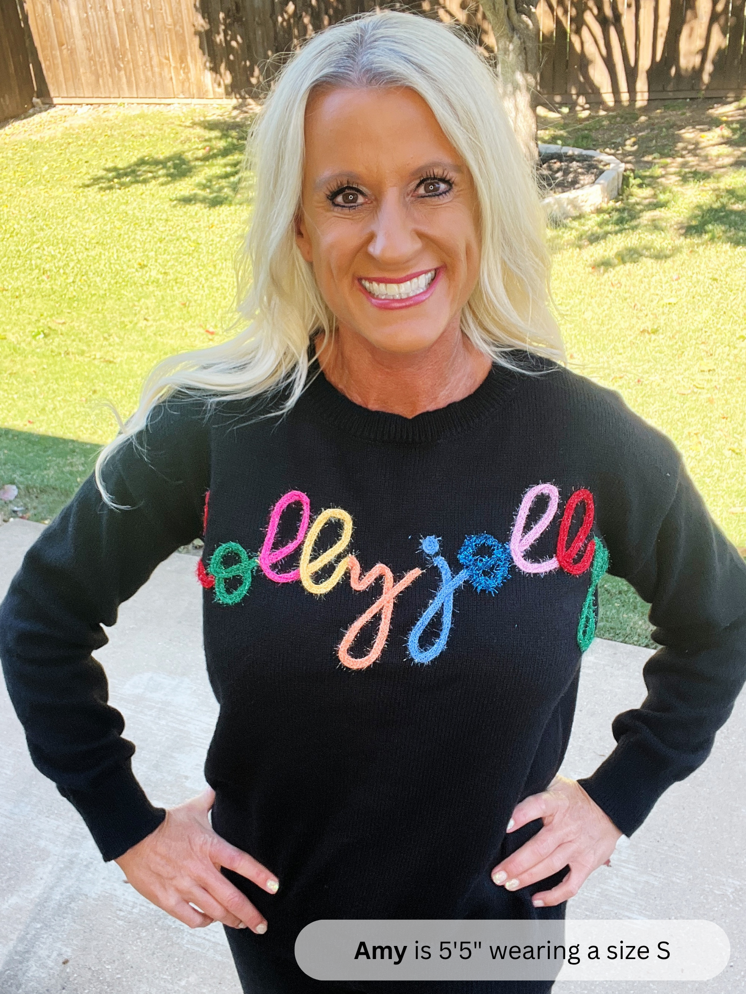 Woman wearing a black sweater with colorful text outdoors
