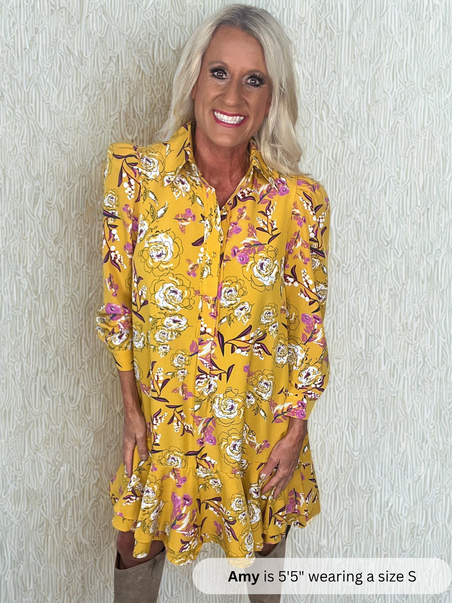 Woman wearing a yellow floral dress against a plain background