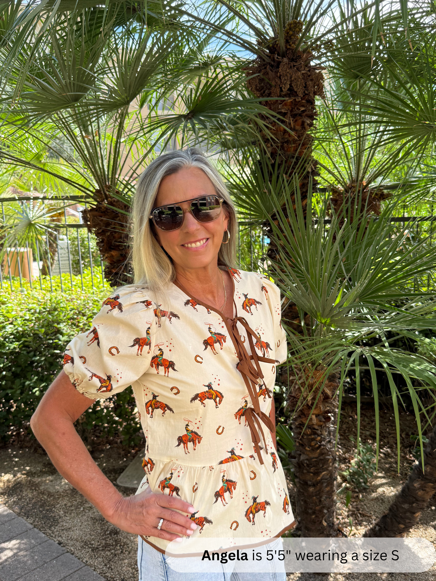 Woman wearing a patterned blouse standing in front of palm trees