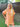 Woman wearing an orange dress standing outdoors with a wooden fence and grass in the background.
