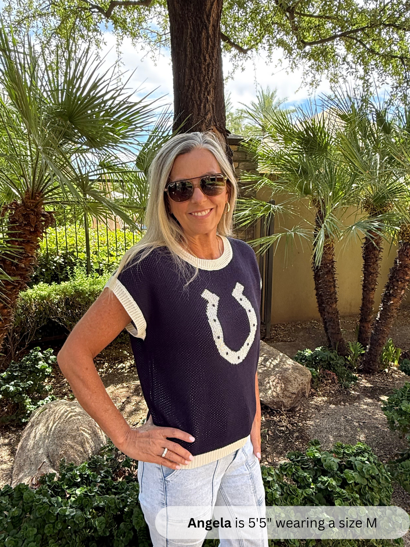 /Navy/ Woman wearing a navy blue shirt with a horse shoe design outdoors