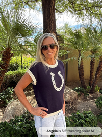 /Navy/ Woman wearing a navy blue shirt with a horse shoe design outdoors