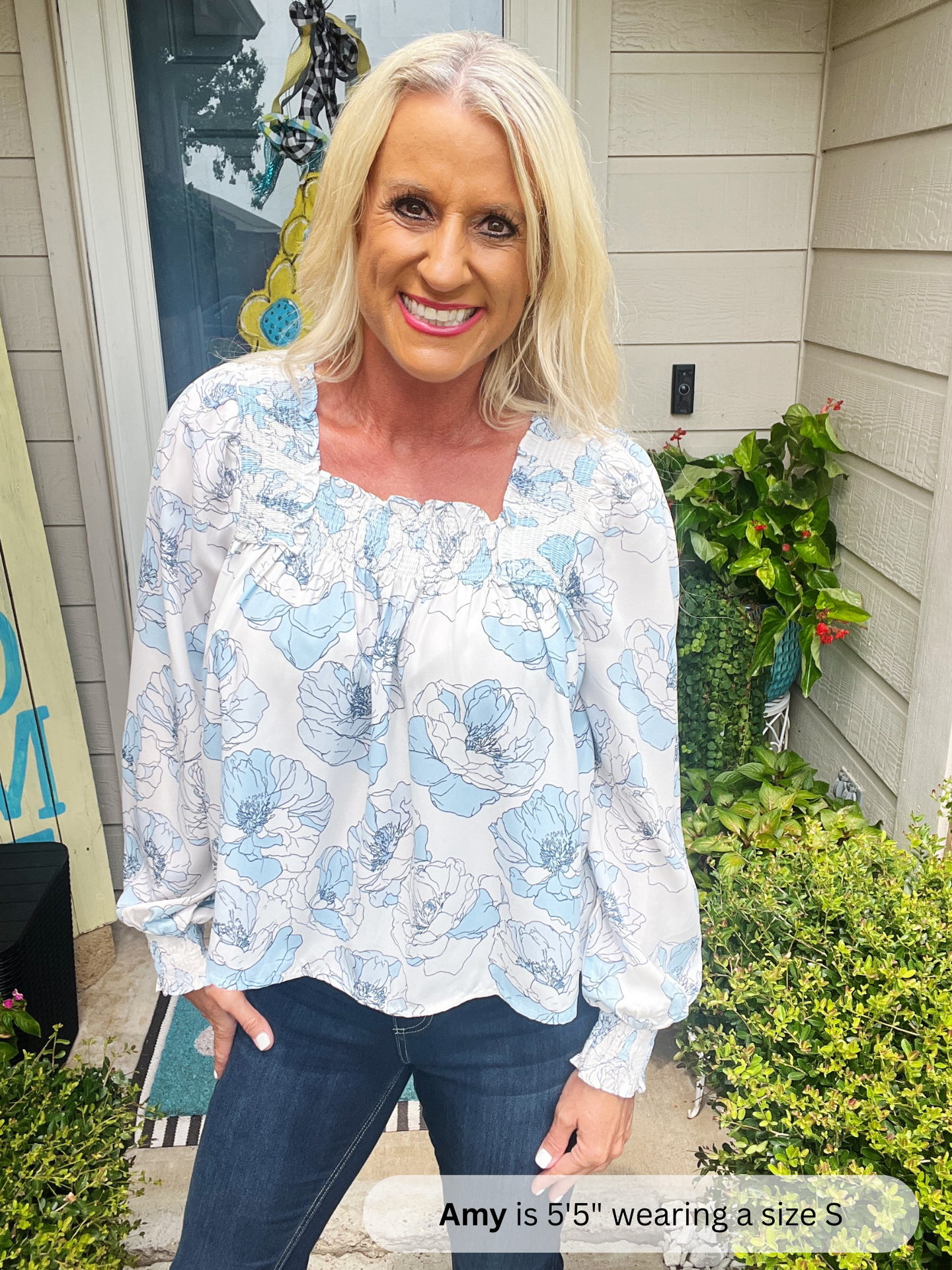 Woman wearing a floral blouse standing outside a house