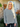Woman wearing a black and white striped sweater standing outside a house.