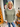 Woman wearing a green sweater and blue jeans standing in front of a decorated door with Halloween decorations.