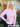 Woman wearing a pink sweater standing outside a house with decorative elements.