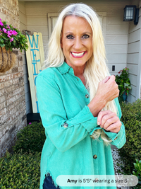 Woman in a teal shirt standing outdoors with decorative elements in the background
