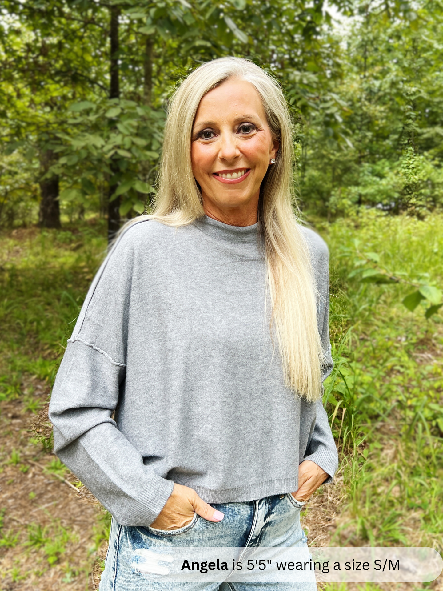 Woman wearing a gray sweater in a forest setting