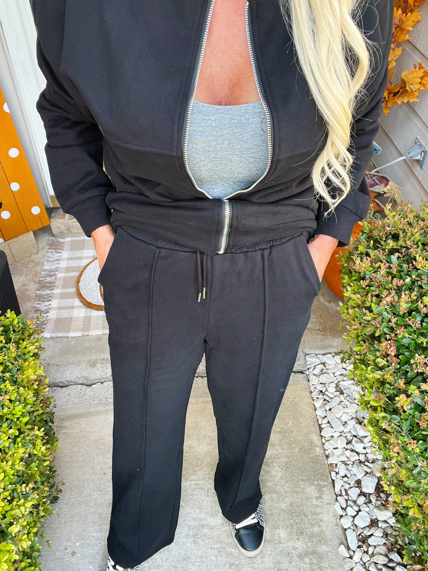 Person wearing a black tracksuit with a partially open front, standing outdoors.