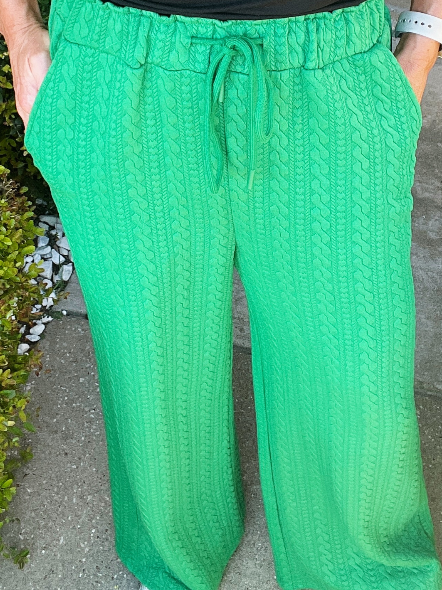 Green textured pants worn by a person on a concrete surface.