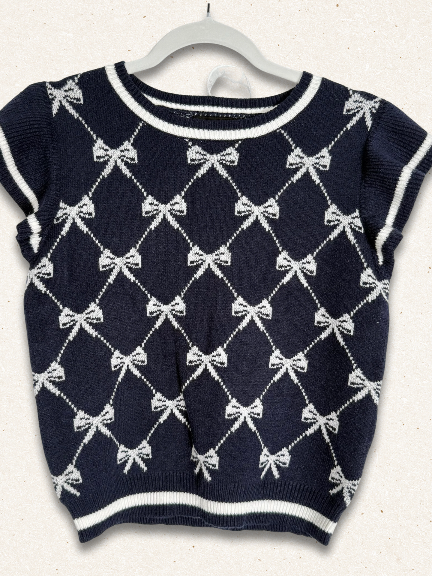 Navy blue sweater with white bow pattern on a white background
