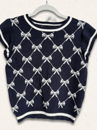 Navy blue sweater with white bow pattern on a white background
