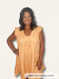 Woman wearing a peach-colored dress on a light background
