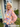 Woman wearing a colorful floral blouse standing outside a house.