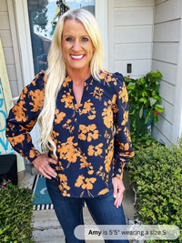 Woman wearing a navy floral blouse standing outside a house