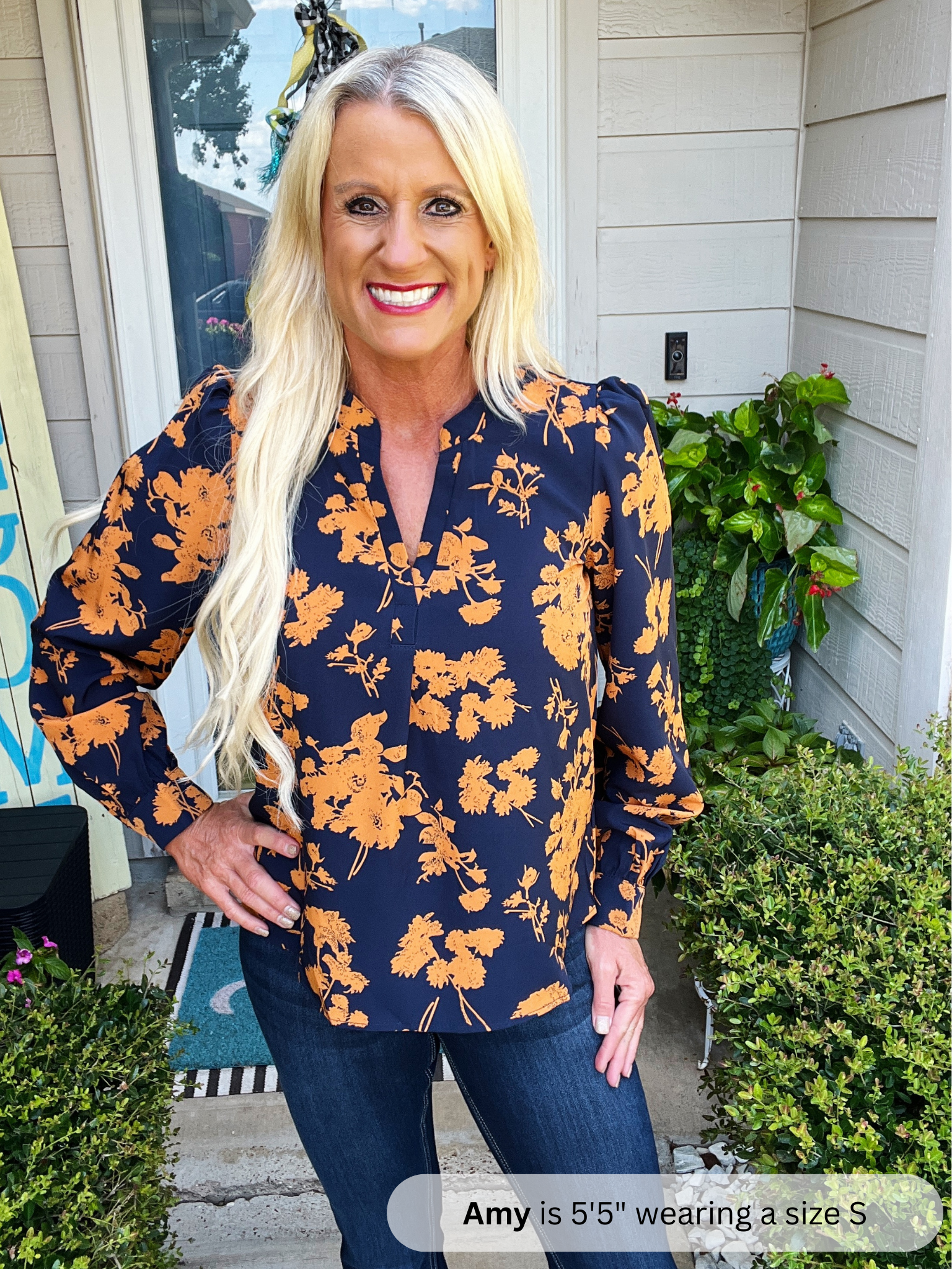 Woman wearing a navy floral blouse standing outside a house