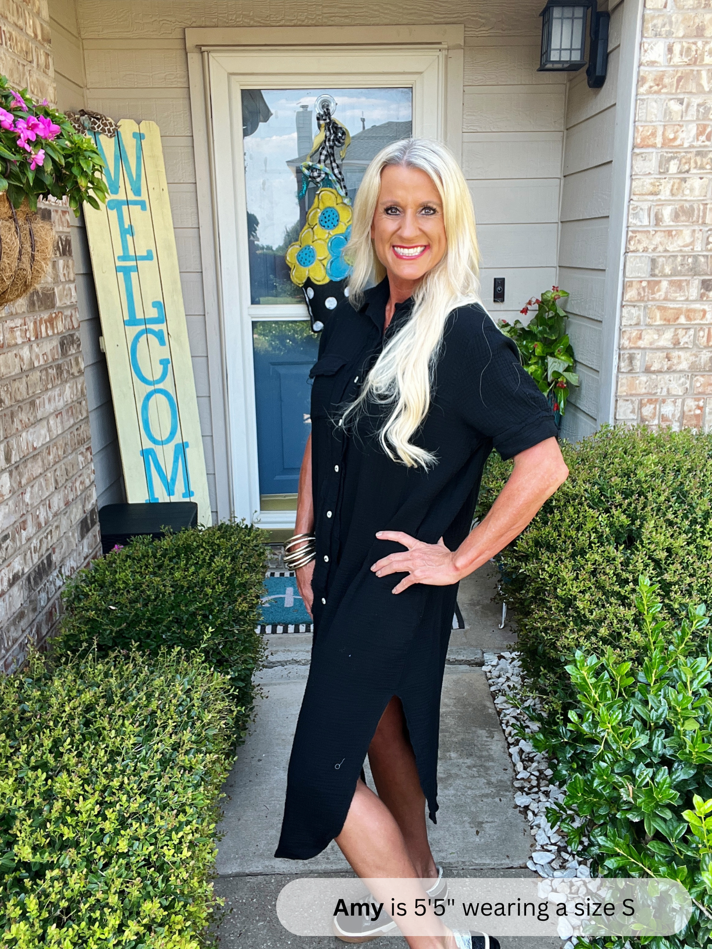 Woman in a black dress standing in front of a house with decorative signs.