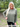 Woman wearing a green long-sleeve top outdoors with a blurred natural background