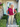 Woman standing outside a house with decorative 'WELCOME' sign and plants.