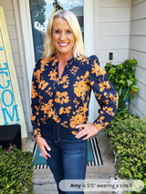 Woman wearing a navy blue floral blouse standing outside a house.