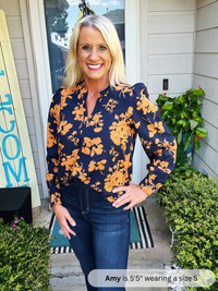 Woman wearing a navy blue floral blouse standing outside a house.