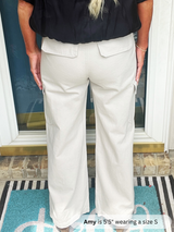 Person wearing light-colored pants and a black top indoors.