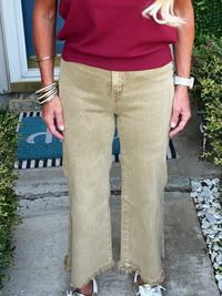 Person wearing a red top and beige pants standing on a porch.