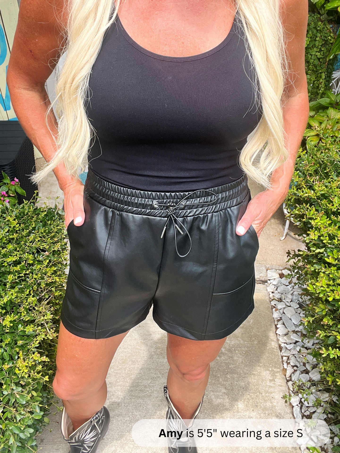 Person wearing a black tank top and black shorts outdoors.