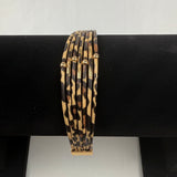 A set of six thin bangle bracelets with a leopard print pattern and small gold accents, displayed on a black bracelet stand.