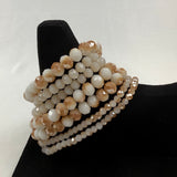 /Beige/ A multi-strand beaded bracelet with alternating light brown and cream faceted beads displayed on a black velvet stand against a white background.