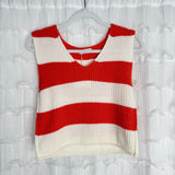A sleeveless knit top with wide horizontal red and white stripes hangs on a clear hanger against a white, ruffled background. The top has a V-neck and a slightly cropped, boxy fit.
