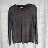 /Ash Black/ A long-sleeved, dark gray ribbed shirt hangs on a clear hanger in front of a white, textured curtain background.