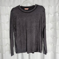 /Ash Black/ A long-sleeved, dark gray ribbed shirt hangs on a clear hanger in front of a white, textured curtain background.