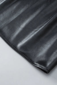 Close-up of the Kara Top by Lovesoft in shiny black faux leather, fully lined for comfort. The smooth texture, subtle reflections, and neat edge stitching are shown as it lies on a light gray surface.