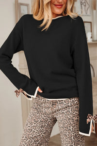 Person wearing a black sweater with leopard print pants in an indoor setting