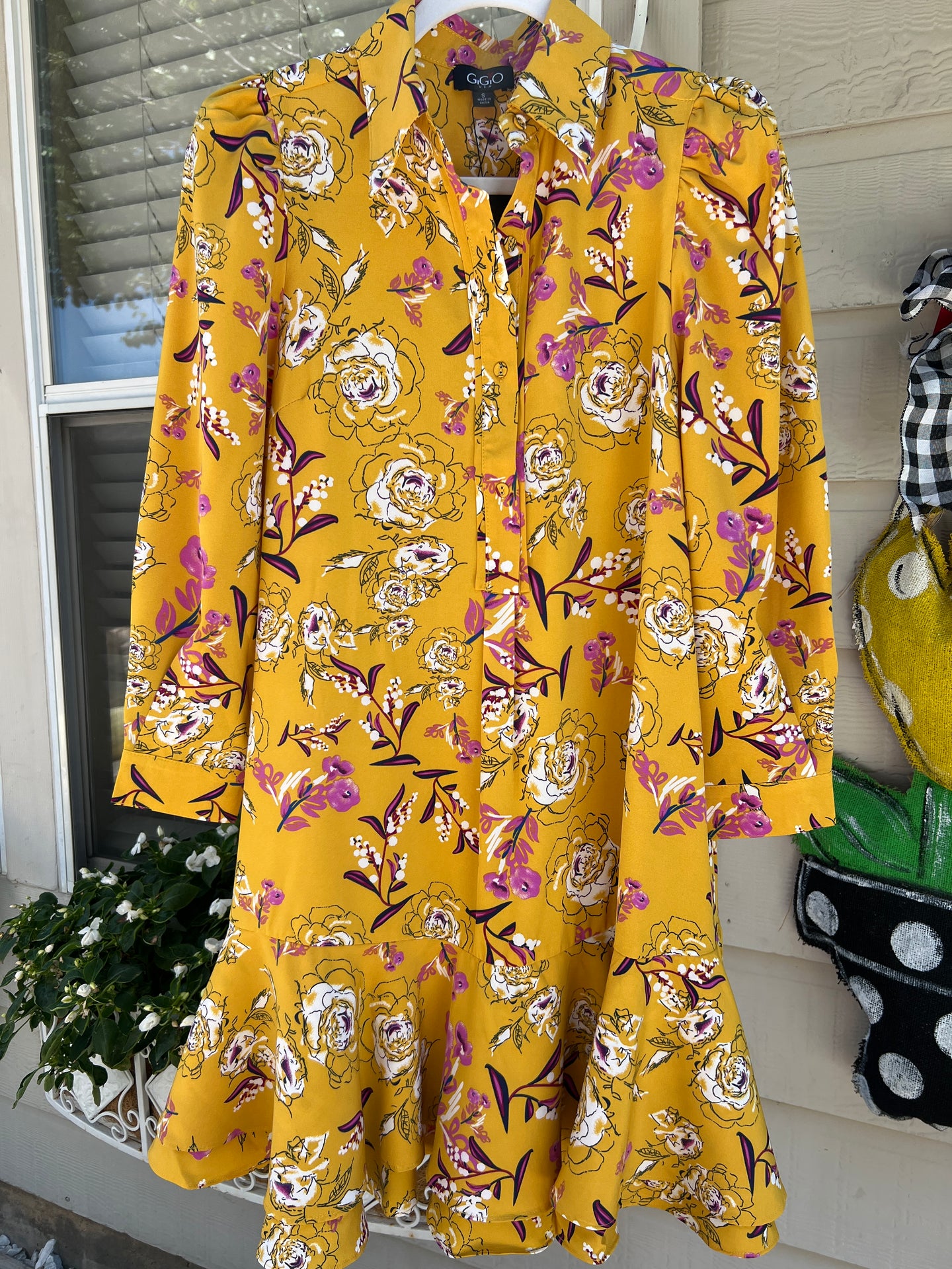 Yellow floral dress on a rack with a neutral background