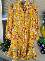 Yellow floral dress on a rack with a neutral background